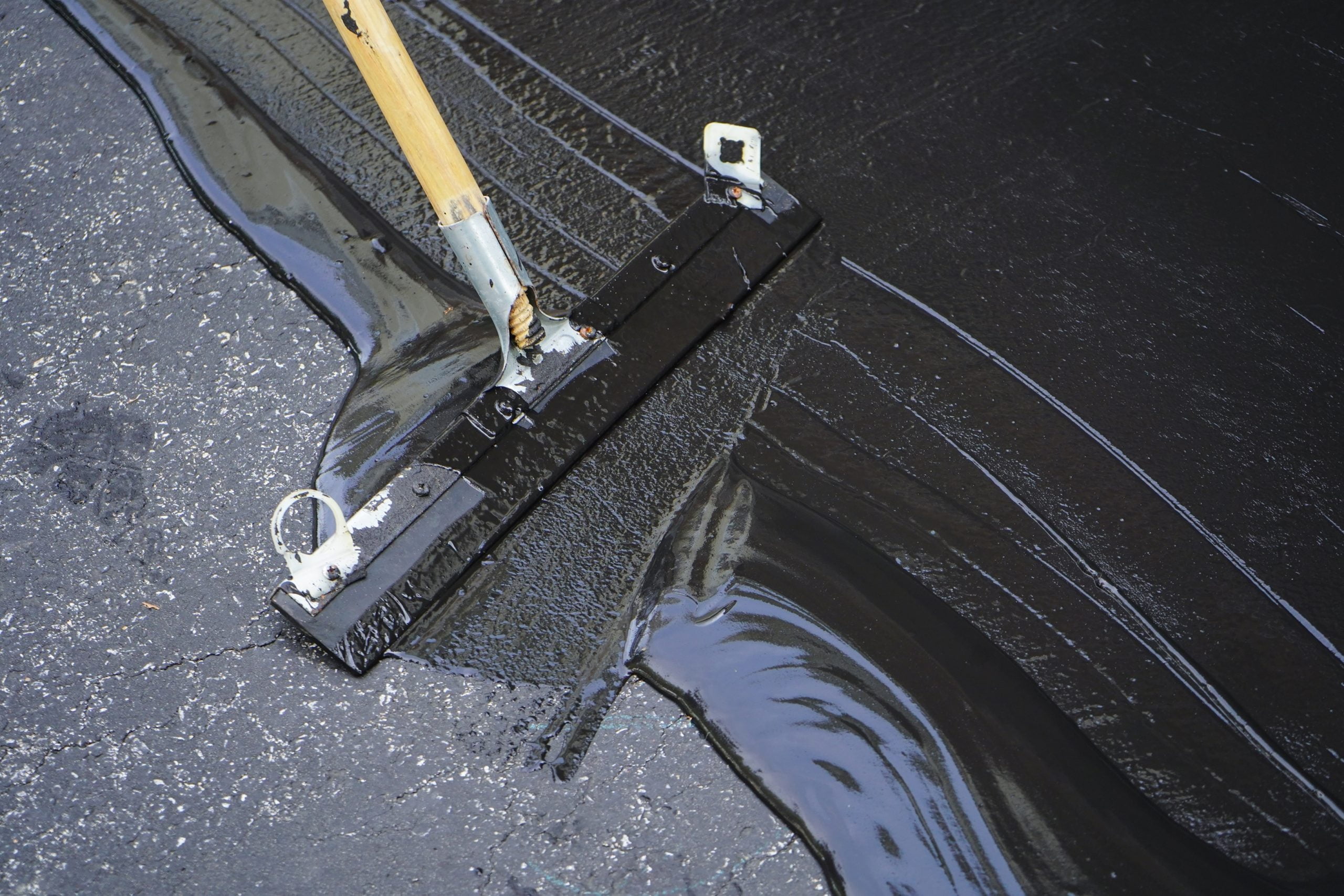 Man sealing asphalt driveway/Sealcoating sealcoating